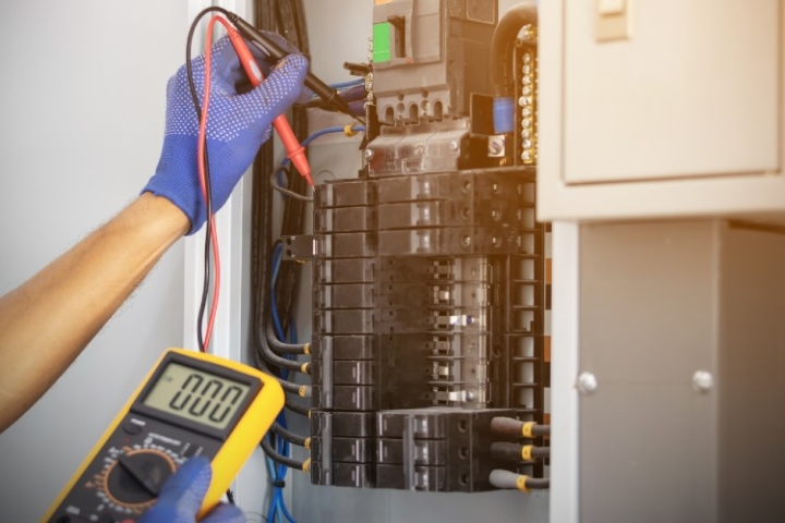 Licensed electrician inspecting a residential electrical panel to support an energy saving AC unit in Loveland Ohio